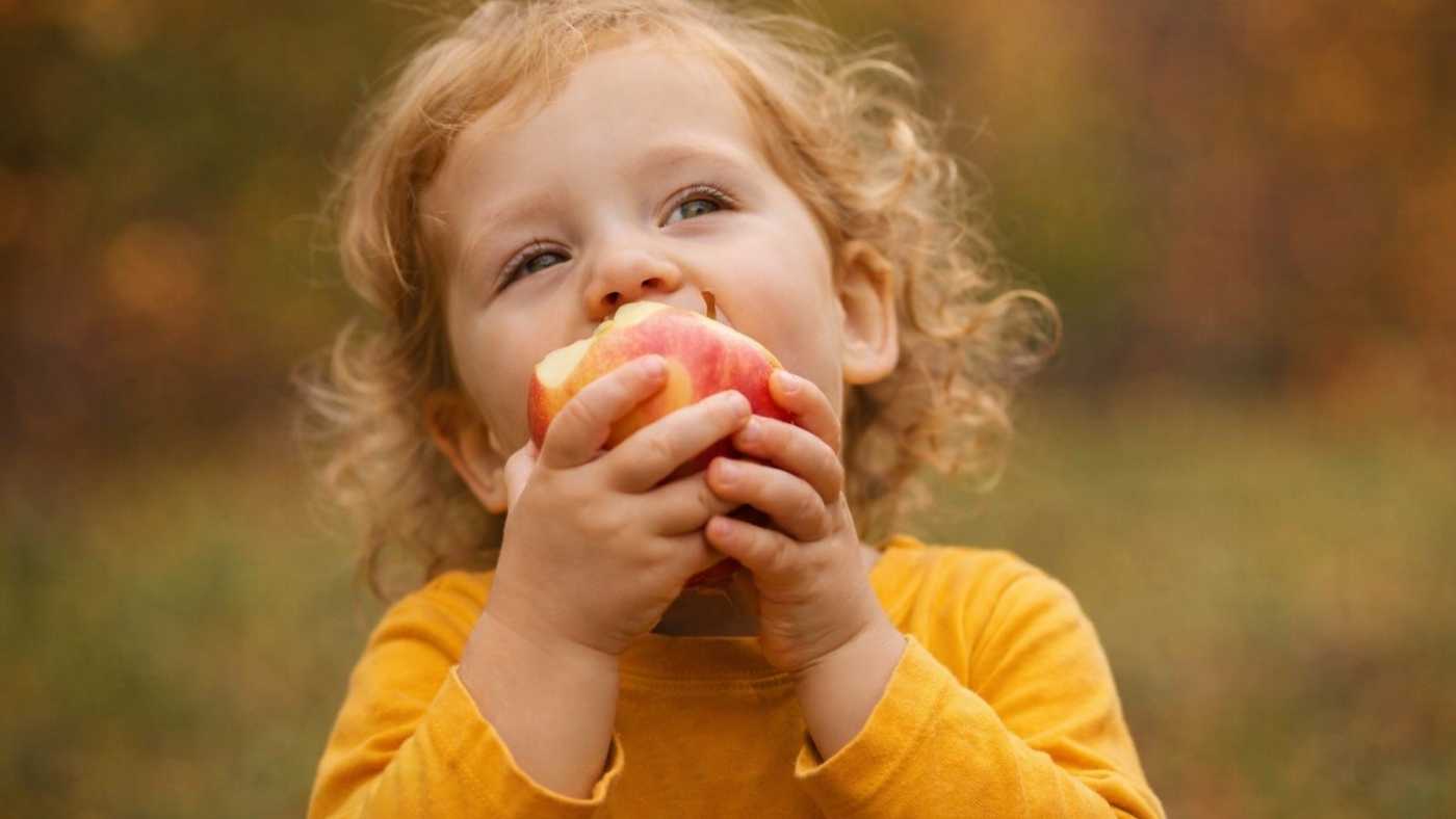 Nena menjant una poma per afavorir l’alimentació i desenvolupament de la parla