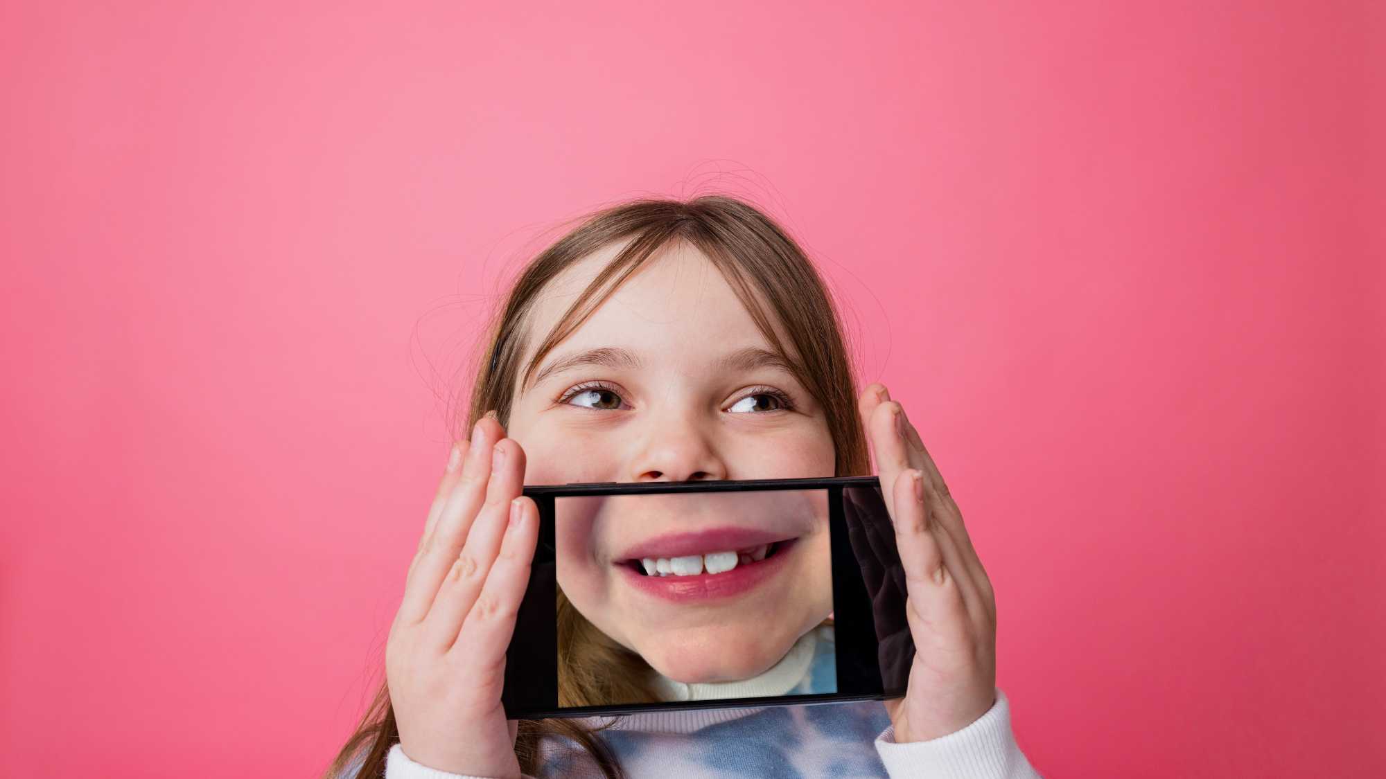 Infant sostenint un telèfon mòbil que mostra una imatge ampliada de la seva boca