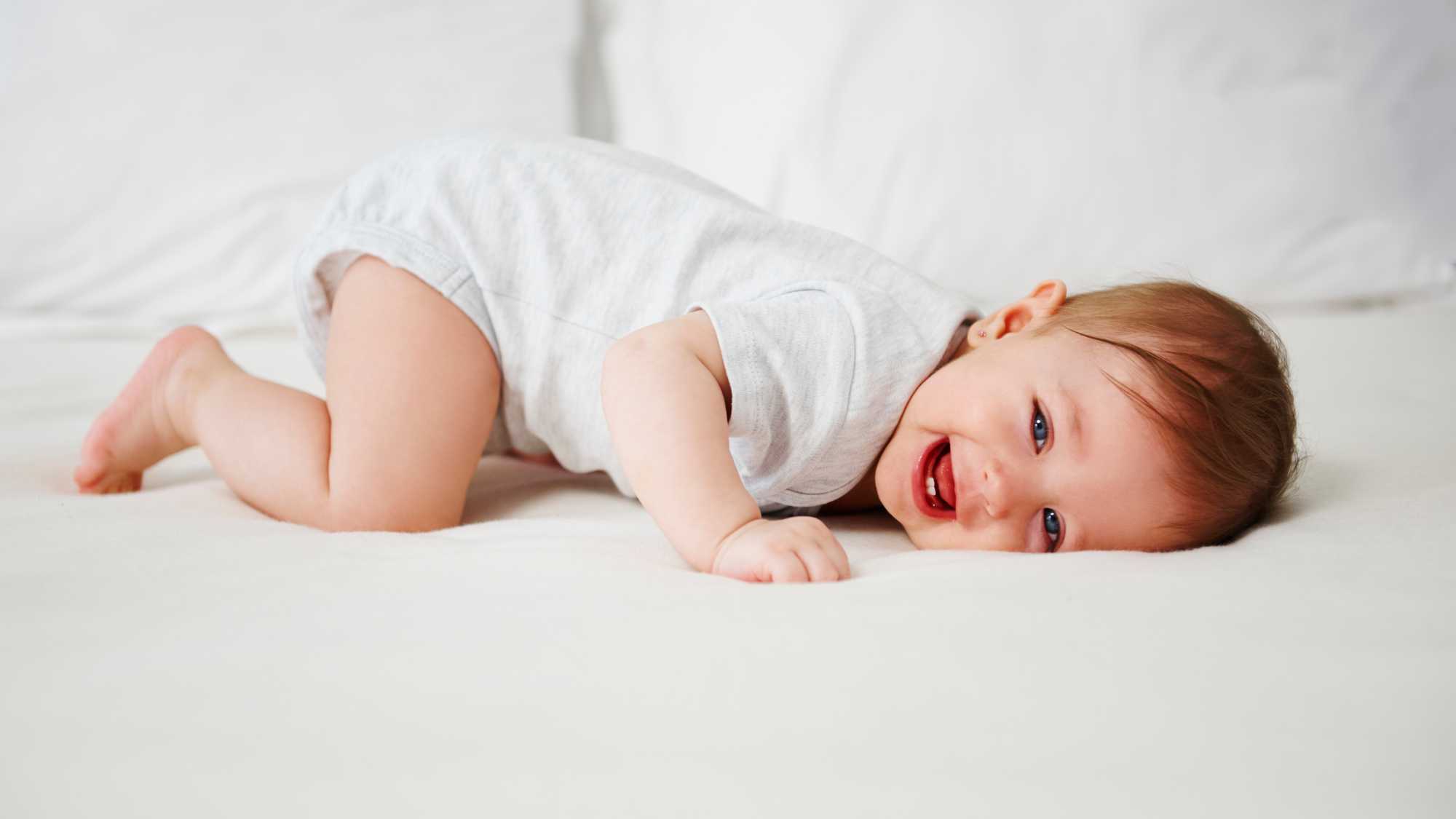 Nadó estirat i somrient en una escena que il·lustra com estimular el llenguatge en nadons de 0 a 1 any